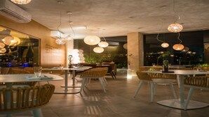 A restaurant interior with round tables, wicker chairs, and hanging pendant lights. - Spacious Gold Coast Townhouse in lush community close to beaches (Noord)