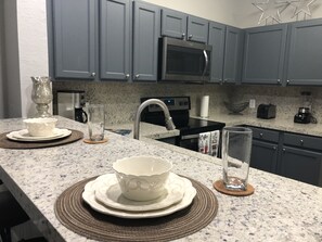 Una cocina con gabinetes grises, un microondas, un tostador y una licuadora sobre la encimera.