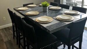 Une salle à manger avec une table rectangulaire dressée pour six personnes, entourée de six chaises.