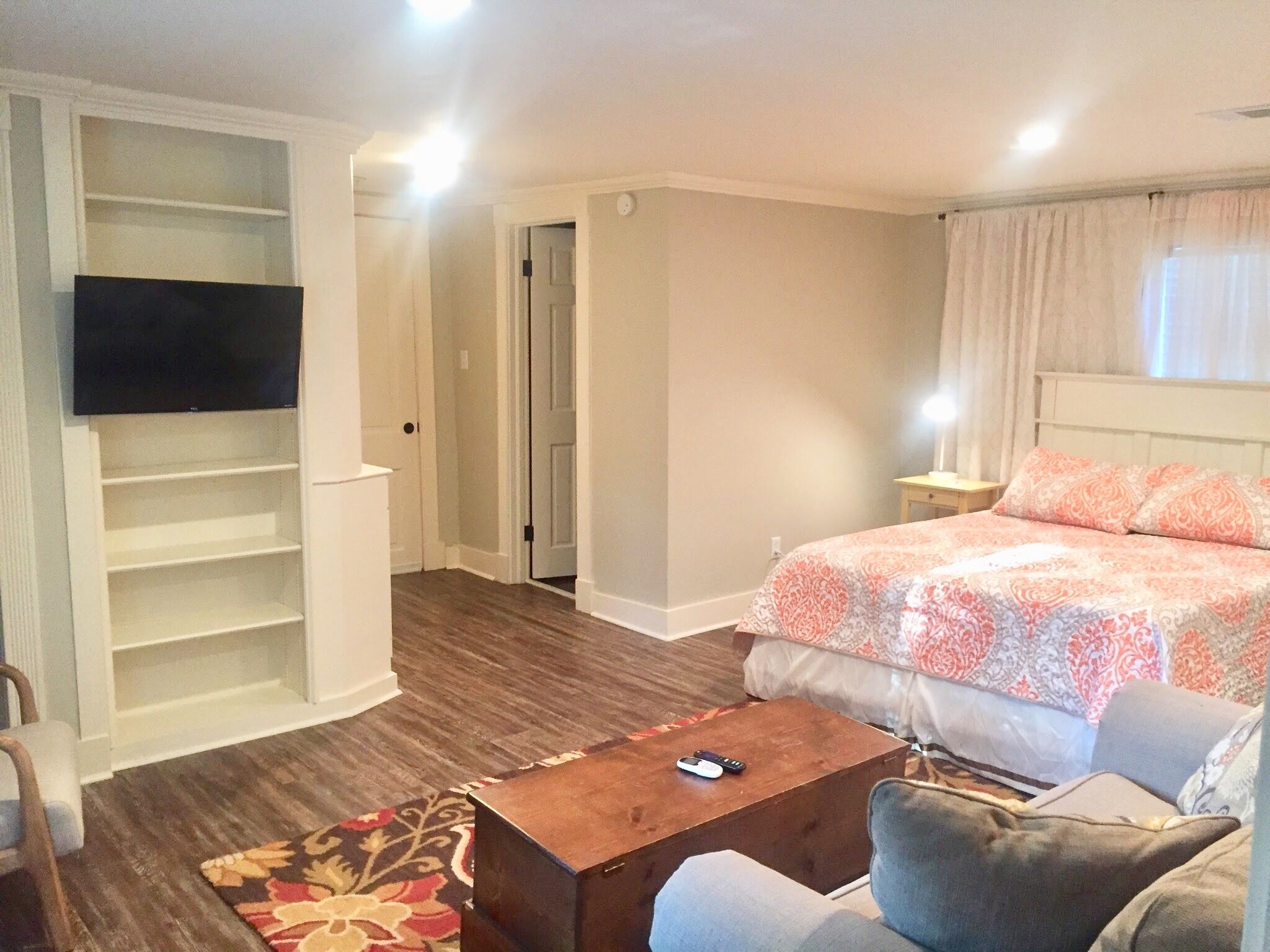 Une chambre d’hôtel avec un lit, un téléviseur fixé au mur, une table basse en bois et un canapé.