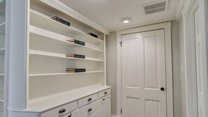 A walk-in closet with white shelving, drawers, and a door.
