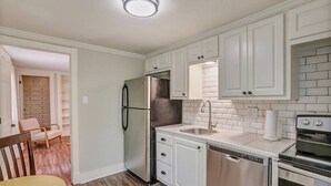 A compact kitchen with white cabinets, stainless steel appliances, and a dishwasher.