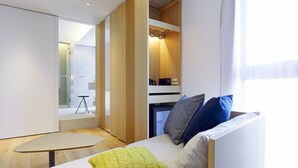 Ein modernes, helles Zimmer mit einer Couch, einem kleinen Tisch und einer Küchenzeile.