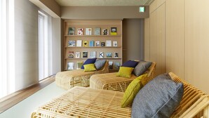 Ein Zimmer mit zwei Korbssofas, einem Bücherregal voller Bücher und einem großen Fenster mit Jalousien.