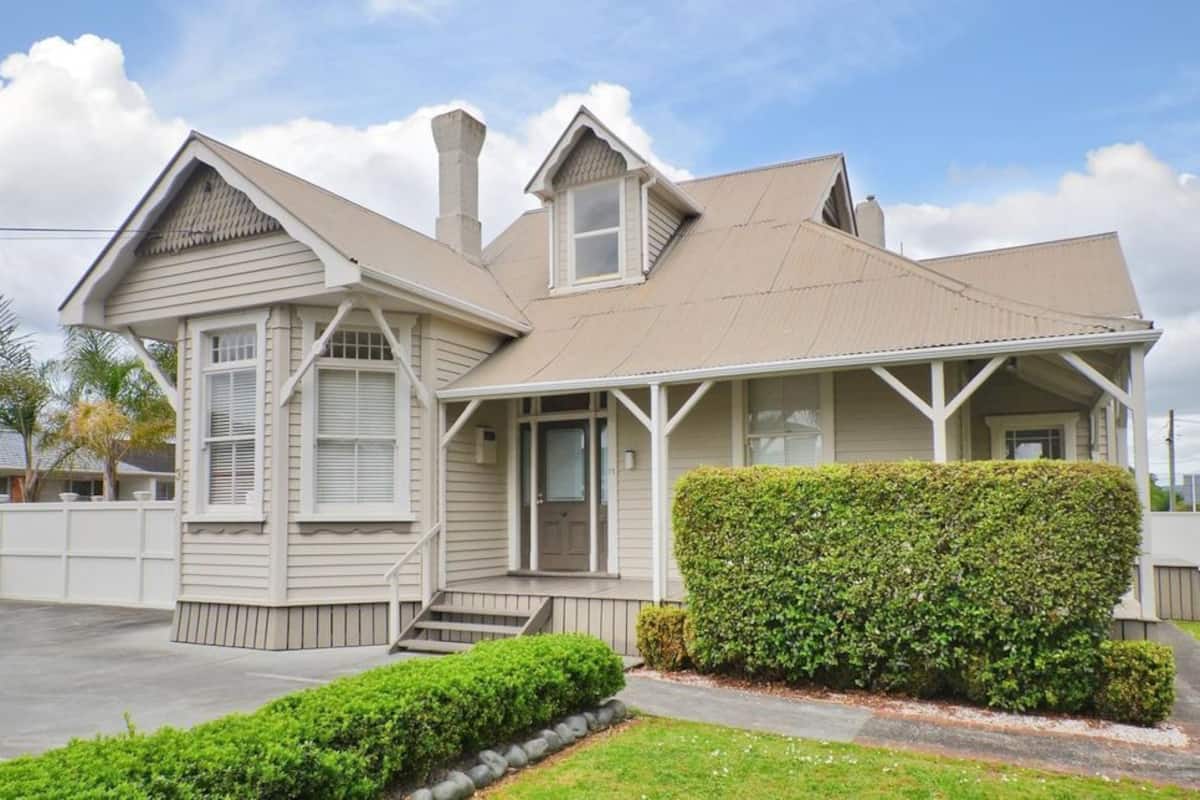 A two-story house with a gabled roof, a front porch, and a well-maintained lawn.