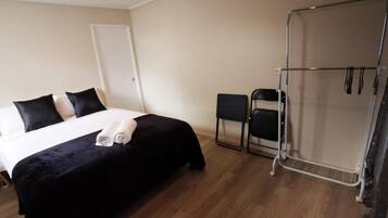 Habitació d'hotel amb llit, una cadira, zona de dutxa i una porta.