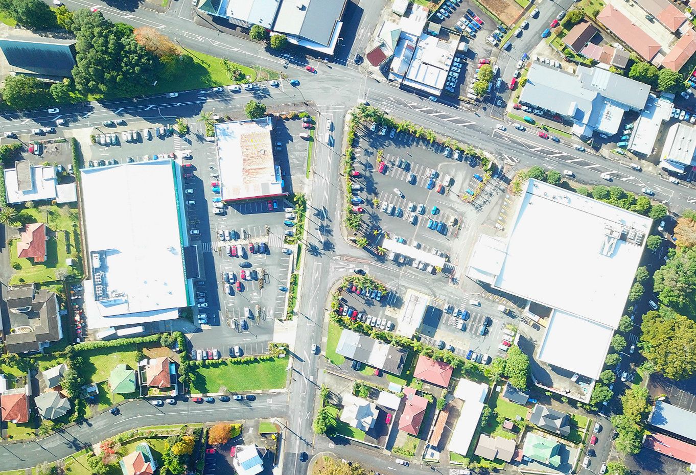 Vista aérea de una zona comercial con estacionamientos, edificios y calles.
