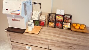 A hotel reception area with a coffee machine, snack dispensers, and a fruit display. - Shuntai Inn (Shoufeng)