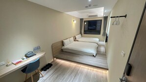 A compact hotel room with a bed, bedside table, and a small desk with a chair. - Shuntai Inn (Shoufeng)