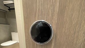 A bathroom with a wooden door, a round mirror, and a modern toilet. - Shuntai Inn (Shoufeng)
