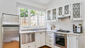 Eine Küche mit weißen Schränken, Edelstahlgeräten, einem Fenster mit Blick und Holzboden.