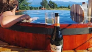 Una persona relajándose en un jacuzzi, con una botella de Valdivieso y una copa sobre una mesa de madera.
