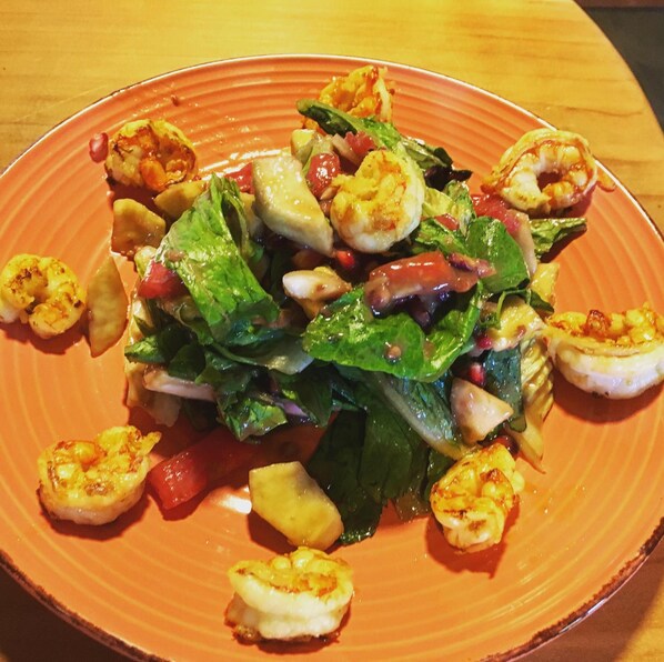 Un plato de comida con camarones, verduras y posiblemente queso.