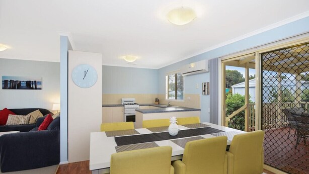 Un espace de vie compact comprenant un coin repas, une kitchenette et une vue sur l’extérieur.