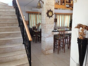 A staircase leading to a dining area with a clock on the wall, a bar area, and a potted plant. - Front beach 3 bedrooms VIlla, huge heated swimming pool 15X5X10 meters L shape (Pomos)