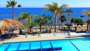 Un área de piscina con vistas al mar, palmeras y un flotador salvavidas.