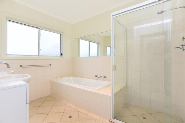 Un baño moderno con bañera, cabina de ducha y ventana que deja entrar luz natural.