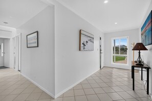 A spacious hallway with white walls, tiled flooring, and two framed artworks.