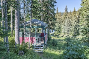 Escape to a secluded cabin surrounded by a lush forest, with a cozy porch and stairs leading to the entrance.