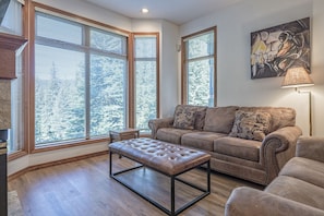 Relax in this stylish living room with a plush leather sofa, matching bench, and a floor lamp.