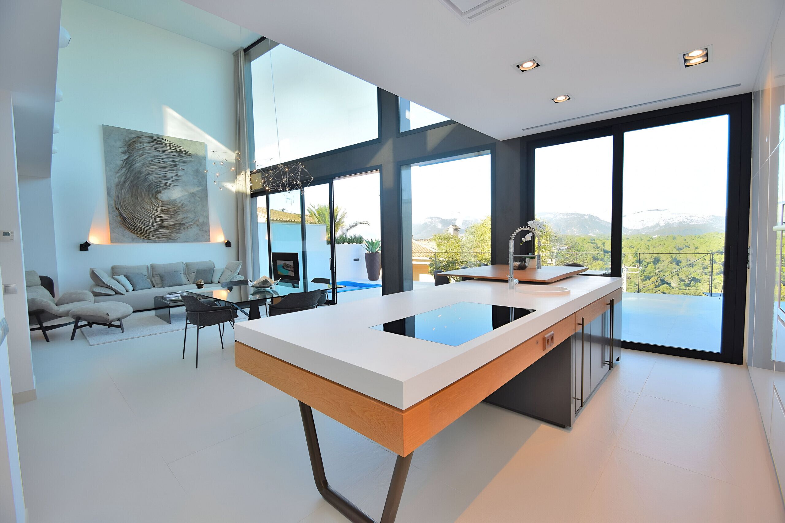 A modern kitchen with a central island, large windows, and a view of the outdoors.