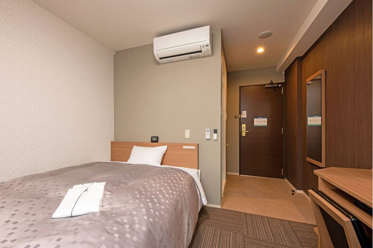 Ein Hotelzimmer mit einem Bett, einer Klimaanlage, einem Holzschrank und einer Tür mit einem Schild.