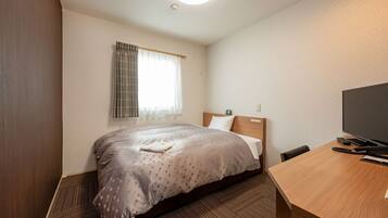 A hotel room with a bed, a desk, a television, and a window with curtains.