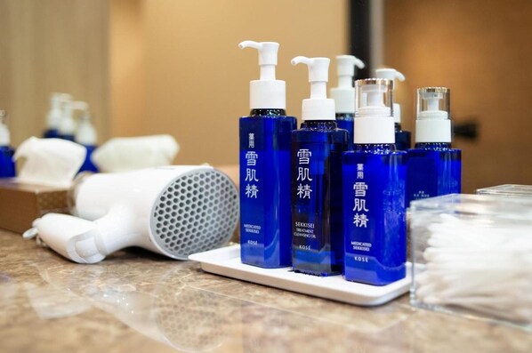 A bathroom counter with various skincare products and a hairdryer.