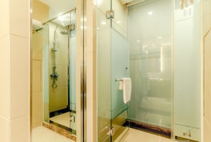Un baño moderno con cabina de ducha de vidrio, toallero visible y puerta de cristal.