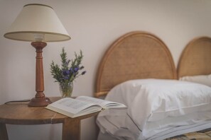 A neatly made bed with white linens, a wooden bedside table with a lamp, and a book open on the table. - Groundfloor apt with al fresco dining, shared pool & wi-fi on awarded winery. (Bucine)
