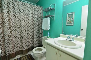 A bathroom with a toilet, sink, and a shower curtain with a polka dot pattern. - Royal Suites New Kingston (Kingston)