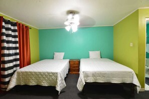 A room with two beds, a ceiling fan, and a window with curtains. - Royal Suites New Kingston (Kingston)