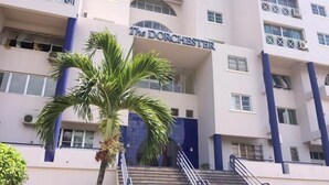 Un edificio con un cartello che riporta "The Dorchester". Presenta diversi piani, balconi e una scala che conduce all'ingresso.