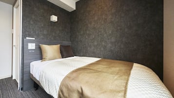 A hotel room with a bed, a headboard, a wall-mounted light, and a carpeted floor.