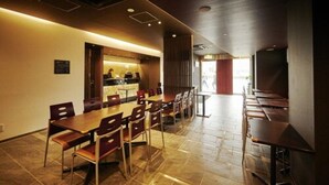 A restaurant with a long counter and multiple tables, a tiled floor, and a modern interior design.