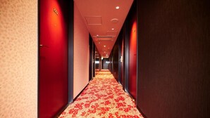 A hotel hallway with red carpet and doors.
