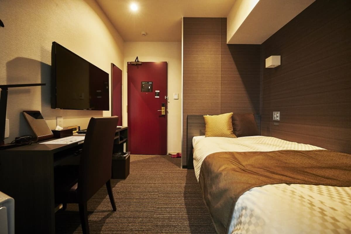 Una habitación de hotel con escritorio, silla, cama y televisor.