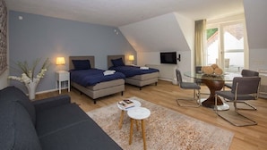 Une chambre moderne avec deux lits, une table à manger en verre et un téléviseur.