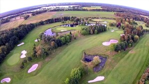 Vue aérienne d’un parcours de golf comportant de nombreux bunkers, des obstacles d’eau et des arbres.