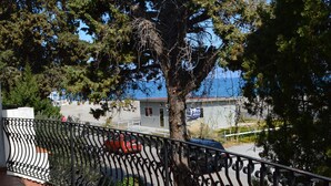 Un balcon doté d’un sol carrelé, d’une rambarde en métal et offrant une vue sur les voitures garées et les bâtiments en arrière-plan.