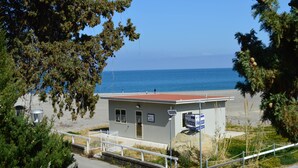 Un petit bâtiment avec un toit rouge, une clôture blanche et une vue sur la mer.