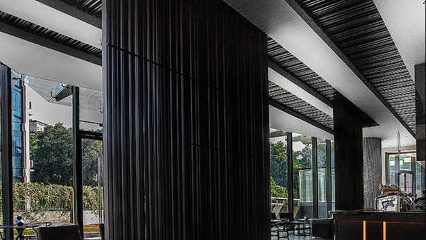 Ein modernes Interieur mit einer zentralen Säule, einer Sitzecke und einer Rezeption.
