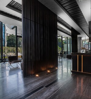 Un interior moderno con una columna central, una zona de estar y un mostrador de recepción.
