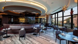 Ein modernes Restaurant mit gewölbter Decke, Sitzgelegenheiten und großen Fenstern mit Blick auf die Stadt.