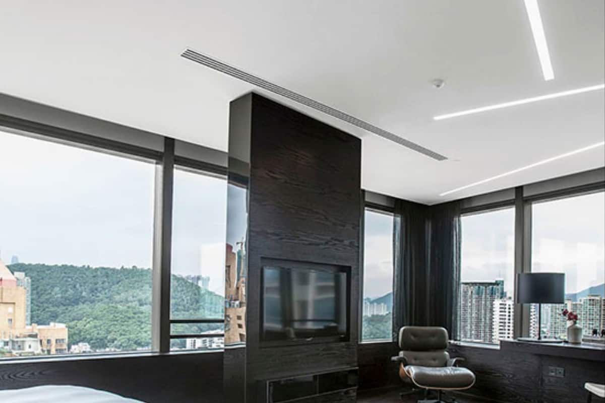 A modern hotel room with a large bed, a TV, and a city view.