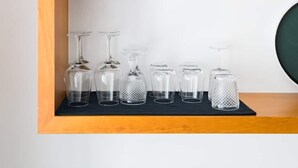 A wooden shelf with a terracotta pot containing a green plant and several clear glassware items. - Modern flat by Time Out Food Market (Very Central) (Lisboa)