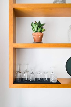 A wooden shelf with a terracotta pot containing a green plant and several clear glassware items. - Modern flat by Time Out Food Market (Very Central) (Lisboa)