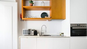 A compact kitchen with white cabinets, a microwave, a sink, and a built-in oven. - Modern flat by Time Out Food Market (Very Central) (Lisboa)