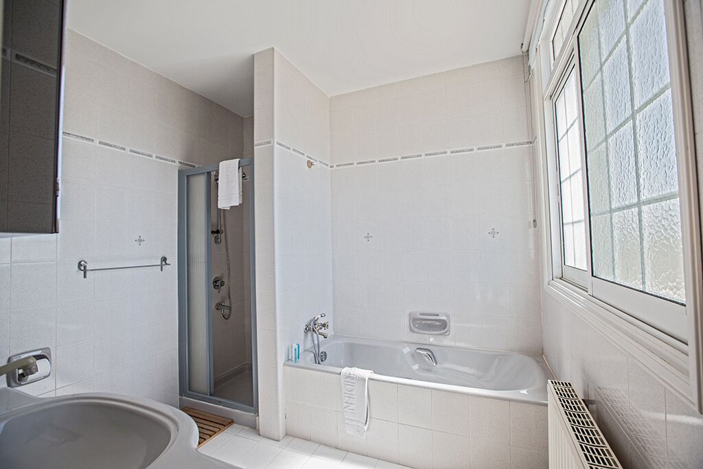 Une salle de bain moderne avec une baignoire, une douche et un espace lavabo séparé.