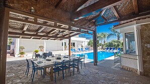 An outdoor dining area with a pool and lounge chairs. - Luxury 5BDR Villa with Private pool, and wheelchair accessible flat (Paralimni)